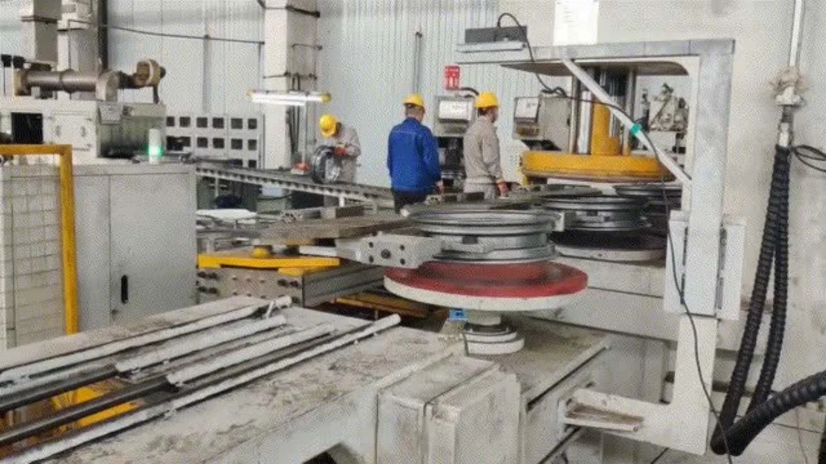 Workers beside a wheel-hub production line fitted with inspection equipment